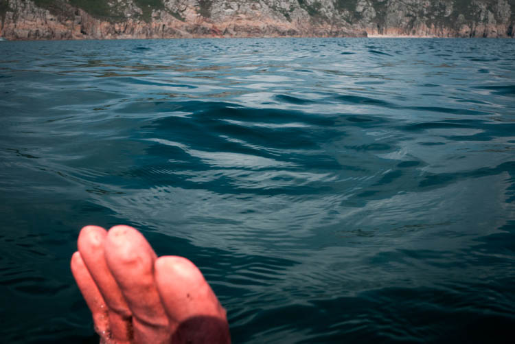 the slightly surreal site of a fisherman's work glove with air trapped in the fingers floating at the surface of the water… 