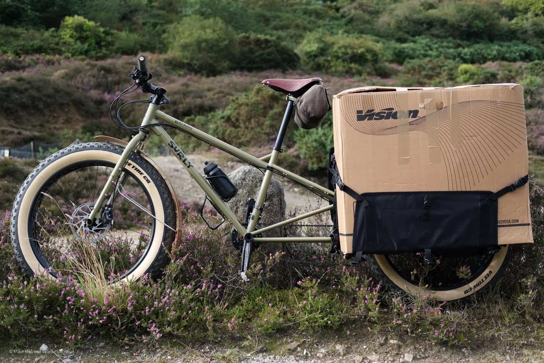 Side image of a Surly Big Fat Dummy with a large cardboard box strapped to the side