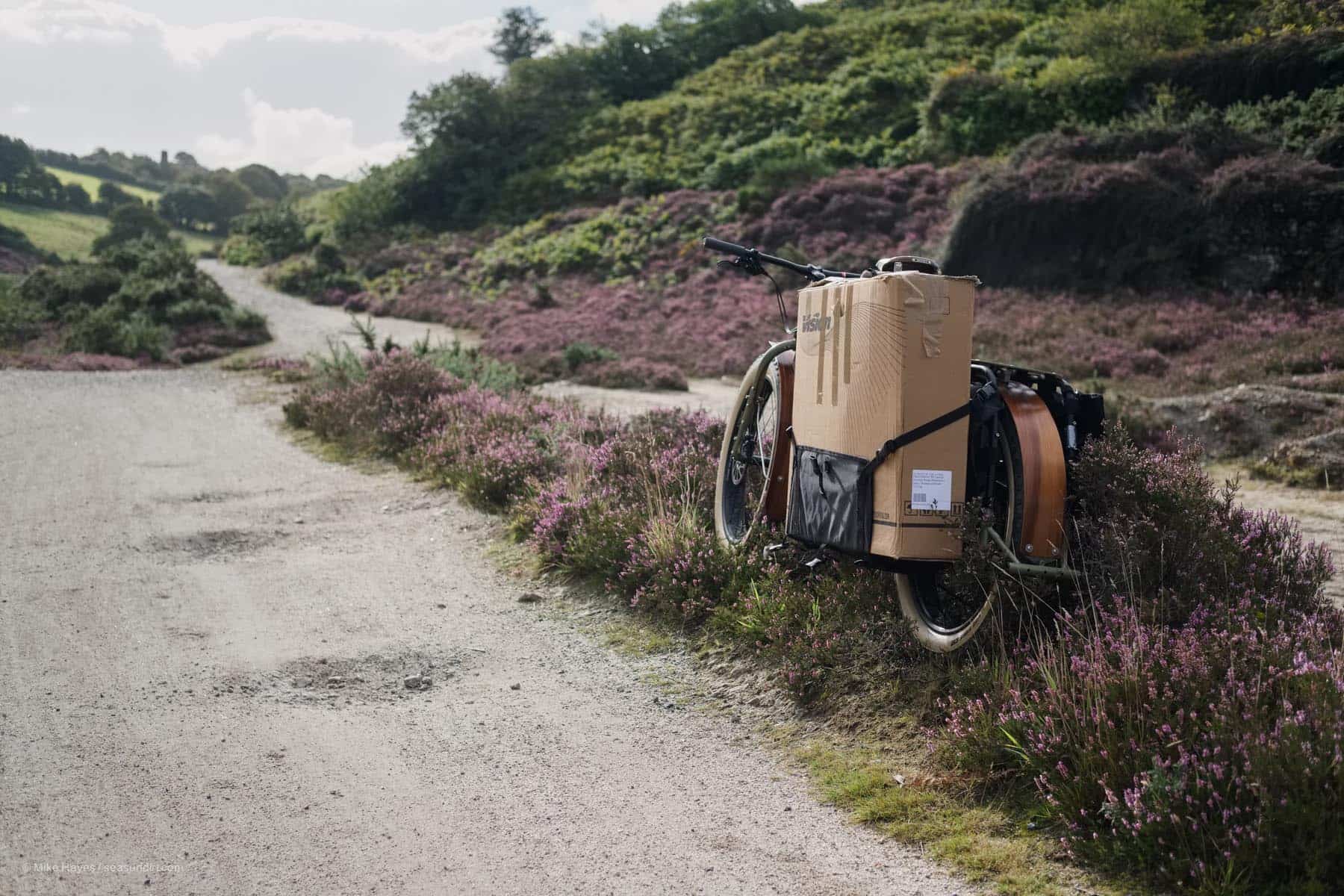 Surly Big Fat Dummy on a dirt track with a large cardboard box strapped to the side