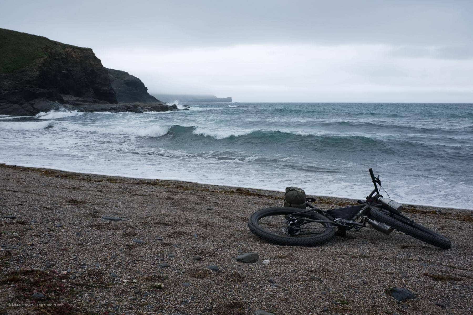 Surly ECR lying on the sand in front of breaking surf on a wet evening