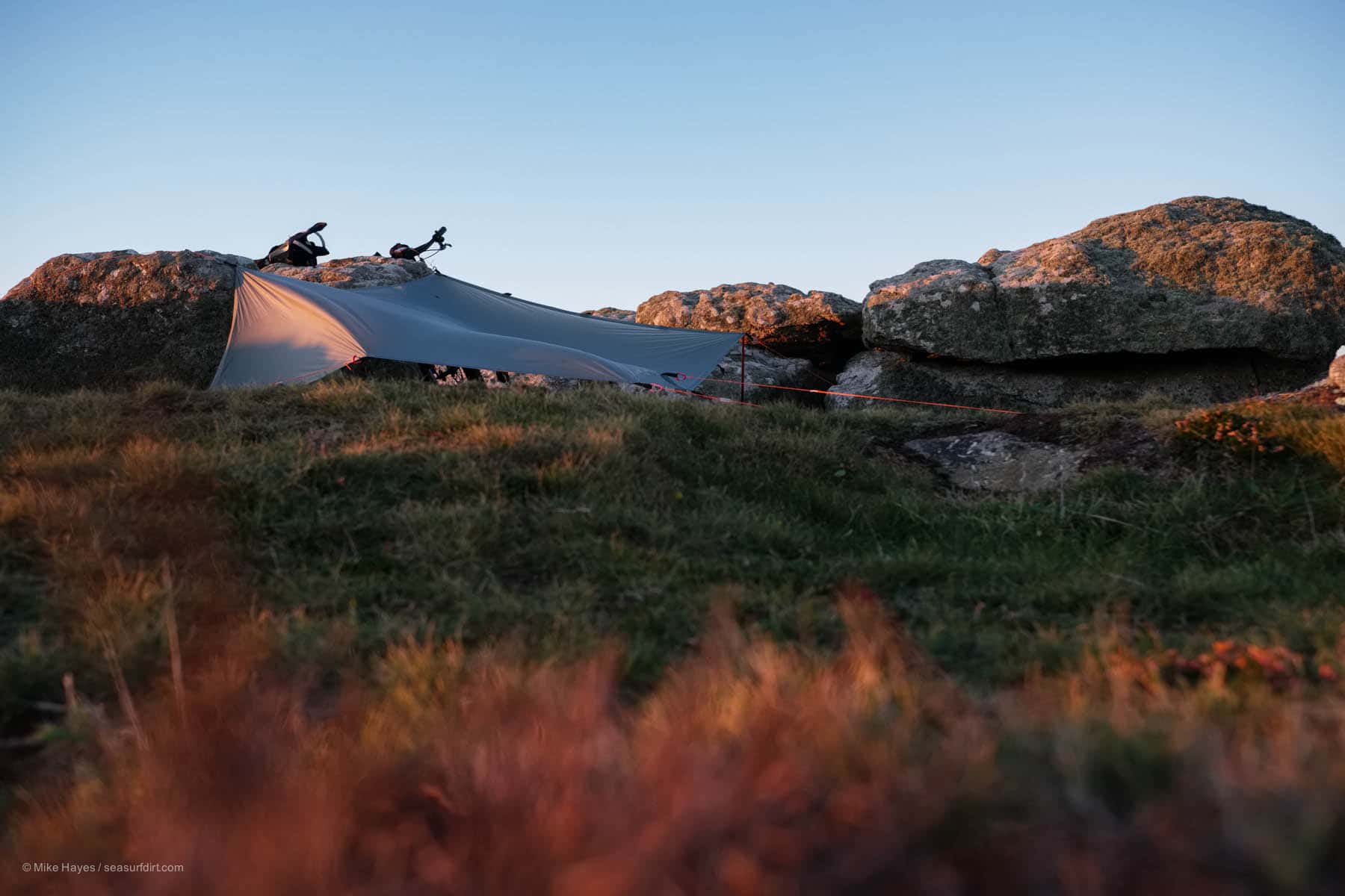 camping tarp stretched across boulders