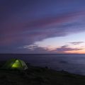 tent pitched in predawn light on the coast