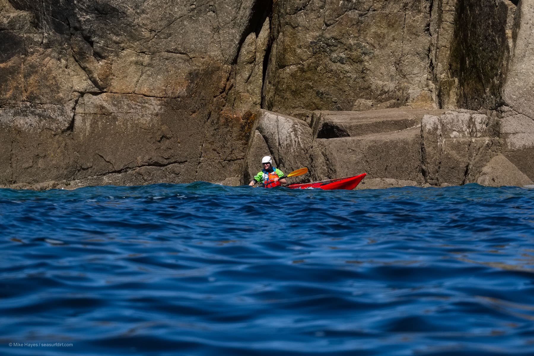Sea kayaker at the base of granite cliffs in west Cornwall