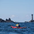 Longships lighthouse and sea kayaker on a sunny day